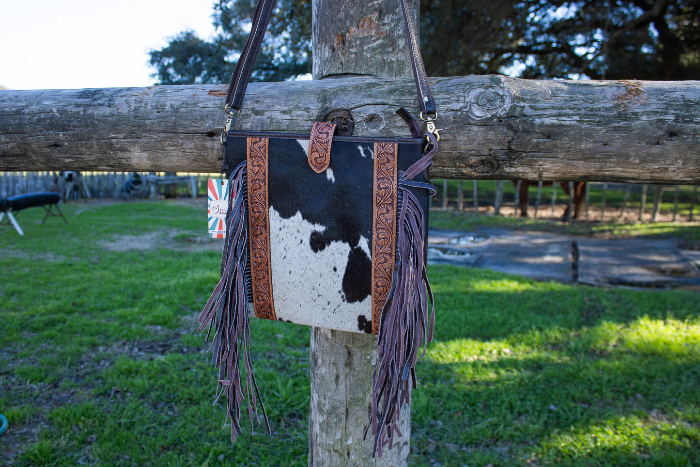 brown and white cowhide purse with brown fringe and tan hand-tooled leather accents 